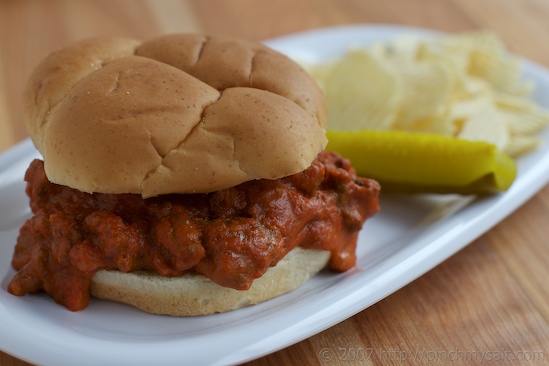 Sloppy Joe Sandwich also known as a Homemade Manwich on a plate with chips and a dill pickle