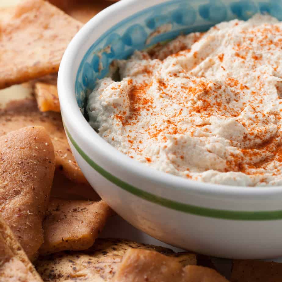 Bowl of smoked tuna dip sitting on a plate with pita chips