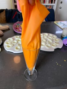 Using a tall glass to fill a piping bag