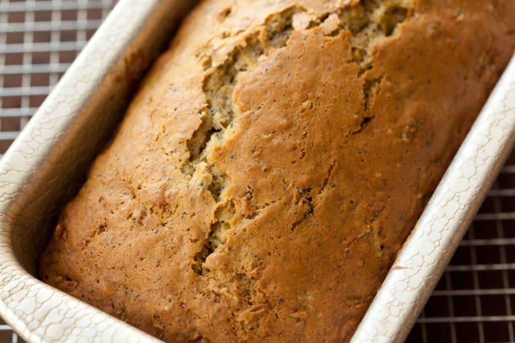Fresh-baked Lemon poppy seed zucchini bread in a loaf pan on a cooling rack